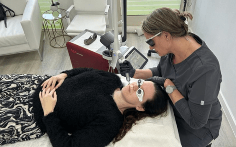 Nuskinnovations - A person lying on a bed with a machine on her face-min